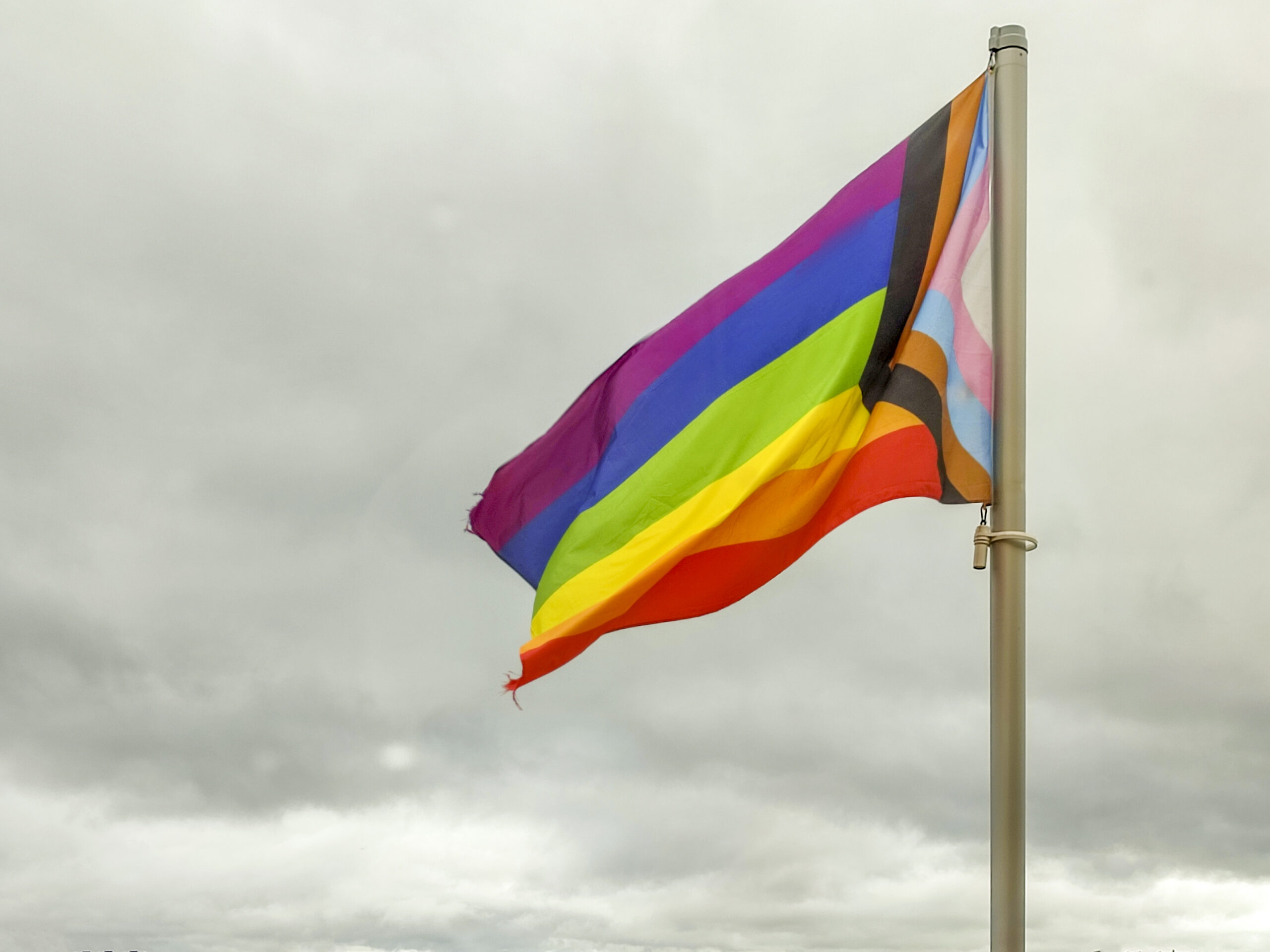 Regenbogenflagge vor dunklem Wolkenhimmel