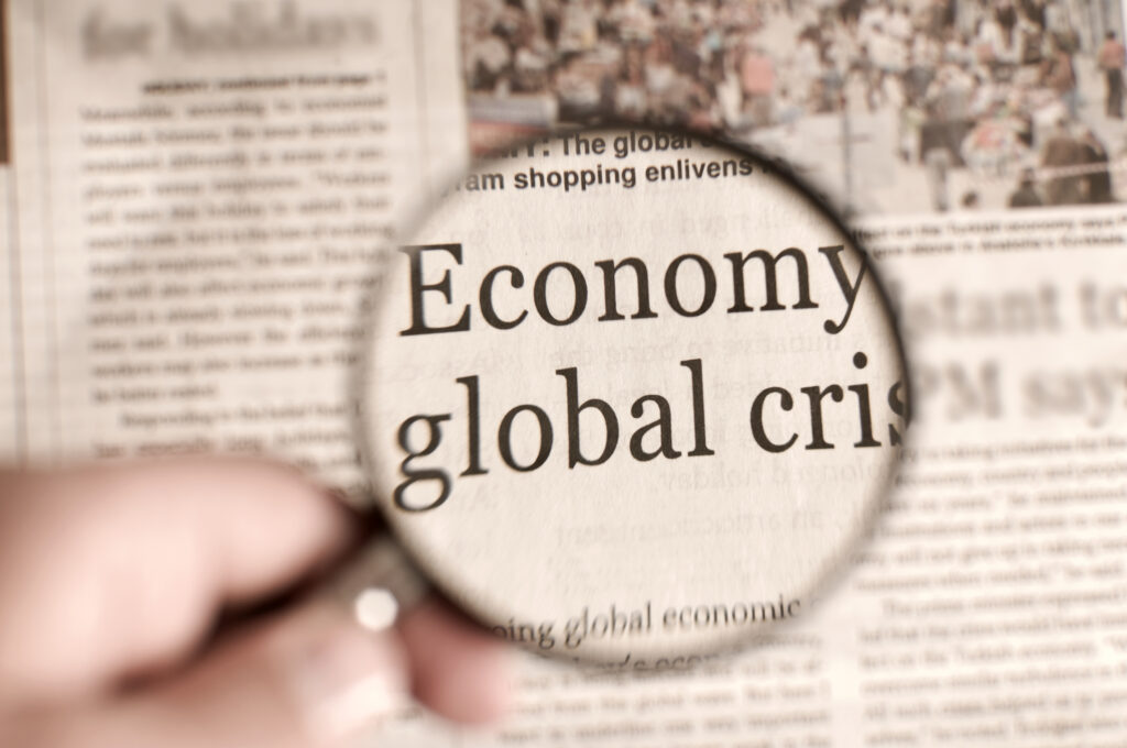 man holding magnifying glass on the financial page of a newspaper