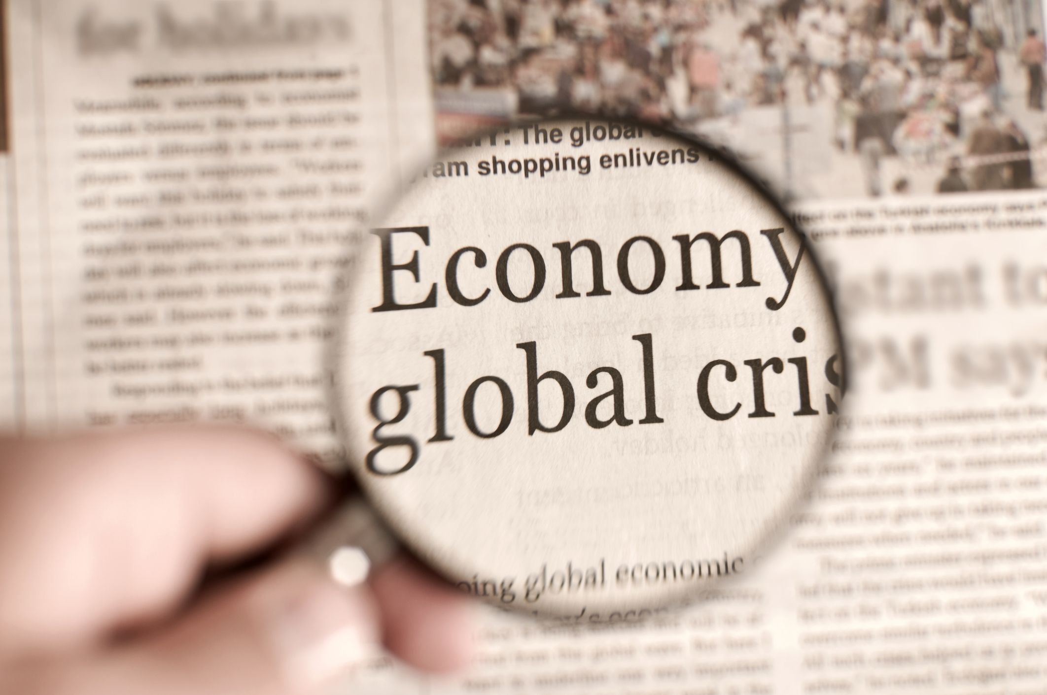 man holding magnifying glass on the financial page of a newspaper